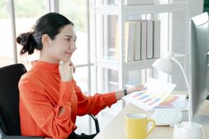 vrouwelijke directeur die op kantoor aan het bureau zit en bedrijfsstatistieken analyseert met diagrammen en grafieken met behulp van de computer foto