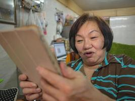 grootmoeder gebruikt haar tablet-videoconferentie om met haar kleinkind te praten foto
