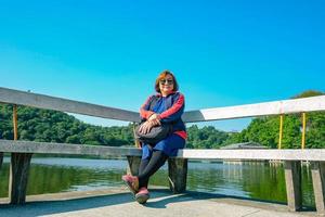 senior vrouwen toerist zittend op stenen stoel naast het meer op de top van de xiqiao berg foshan city china foto