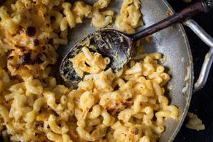 macaroni en kaasnoedels in schaal met lepel op lege plek plat gelegd foto