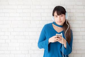 mooi portret aziatische jonge vrouw staande gelukkig genieten en plezier luisteren muziek met koptelefoon op cement betonnen achtergrond, levensstijl van meisje ontspannen geluid radio met oortelefoon, technologie concept. foto