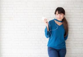 mooi portret aziatische jonge vrouw staande gelukkig genieten en plezier luisteren muziek met koptelefoon op cement betonnen achtergrond, levensstijl van meisje ontspannen geluid radio met oortelefoon, technologie concept. foto