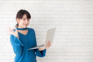 mooie freelance jonge aziatische vrouw zelfverzekerd met behulp van laptopcomputer online internet met succes, blogger meisje uitdrukking van opgewonden met prestatie van werk en trots op triomf. foto