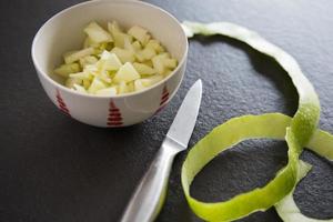 gehakte appel in een witte en rode kom. ingrediënt om heerlijke koekjes te maken foto