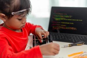 azië studenten leren thuis in het coderen van robotauto's en elektronische bordkabels in stam, stoom, wiskunde engineering wetenschap technologie computercode in robotica voor kinderen concept. foto