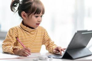 zelfisolatie van kinderen met tablet voor zijn huiswerk, kind doet met behulp van digitale tablet informatie zoeken op internet tijdens covid 19 lock-down, thuisonderwijs, sociale afstand, e-learning online onderwijs foto