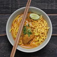 khao soi recept, khao soi, khao soi kai, thai noedels khao soi, kip curry met kruiden geserveerd op houten tafel foto