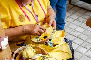 close-up handen van dames demonstreren naaien en decoreren van kleding door borduurraam voor studenten in het huishouden klasse. foto