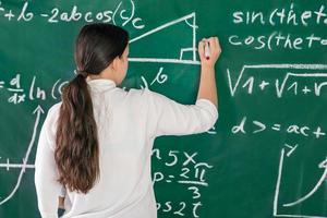 meisje schrijft wiskundige voorbeelden op het schoolbord. lost een geometrieprobleem op. foto