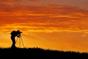 het silhouet van een professionele fotograaf is gericht op het fotograferen in een prachtige weide. foto