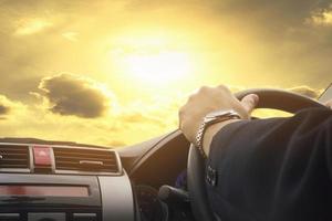 man rijdt in een auto op zonnige dag met gouden lucht en wolkenachtergrond foto