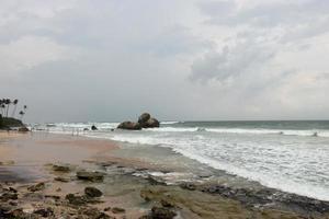 fantastische rotskust. zee golven impact rotsachtig op het strand. zeegolven en bubbels gegenereerd door de rokcs foto