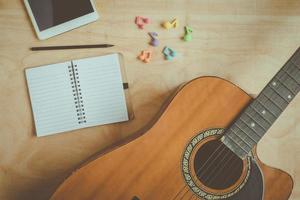 bovenaanzicht van akoestische gitaar met lege notebook op houten tafel background.vintage effect style picture foto