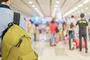 zacht gerichte foto van reiziger over vage lange passagiersrij die wacht op inchecken bij incheckbalies op luchthaven