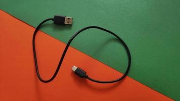 witte spanningsoplader met usb-kabel voor telefoon en gadgets opladen op gekleurde en oplichtende achtergrond foto