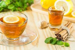 thee met munt honing kaneel en citroen op hout achtergrond foto