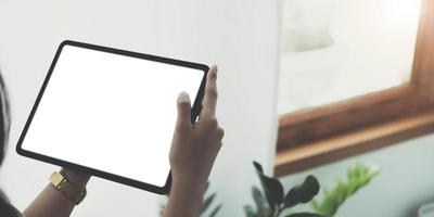 mockupbeeld van de hand van de vrouw met zwarte tablet-pc met leeg wit scherm in houten café foto