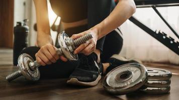 vastberaden vrouw die thuis gewicht verliest en traint met halters. sport- en recreatieconcept. mooie vrouw in sportkleding foto