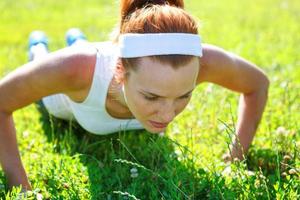 jonge vrouw doet push-ups op groen gras. foto