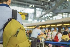 zacht gerichte foto van reiziger over vage lange passagiersrij die wacht op inchecken bij incheckbalies op luchthaven