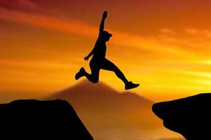 silhouet van een atleet die op een rotsachtige klif springt foto