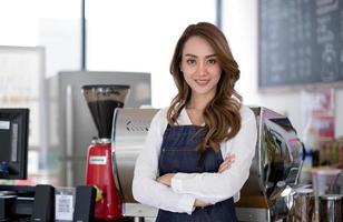 startup succesvolle kleine ondernemer mkb schoonheid meisje staan met tablet smartphone in coffeeshop restaurant. portret van aziatische tan vrouw barista café-eigenaar. MKB ondernemer verkoper bedrijfsconcept foto