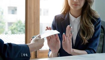 een professionele Aziatische vrouwelijke advocaat of bedrijfsjuridisch adviseur weigert steekpenningen of geld van haar cliënt. ent of eerbetoon betalingsconcept foto