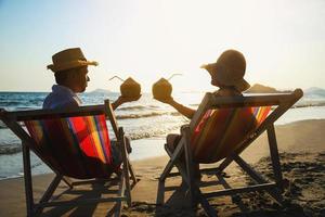 ontspannen paar gaan liggen op strand stoel met zee golf achtergrond - man en vrouw hebben vakantie op zee natuur concept foto