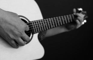 close-up van de man die gitaar speelt in zwart-witte toon foto
