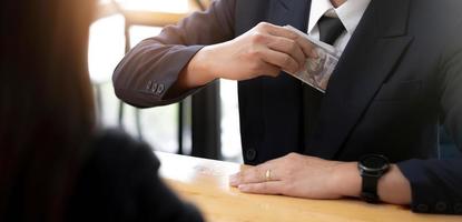 een zakenman neemt een bankbiljet van een dollargeld in de zak van zijn pak. corruptie en omkoping concept. bijgesneden afbeelding foto