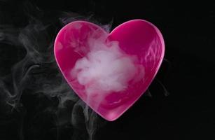 rook van droogijs met roze hartvormige beker geïsoleerd op zwarte achtergrond foto