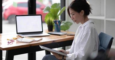 portret van een gelukkige Aziatische onderneemster die aan tabletcomputer werkt foto