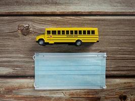 schoolbus en masker op houten tafel voor onderwijs of medisch concept foto