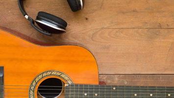 bovenaanzicht werkruimte met hoofdtelefoon en akoestische gitaar op houten tafel achtergrond. foto