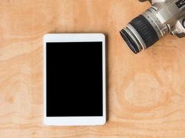 bovenaanzicht van tablet met camera op houten tafel. foto