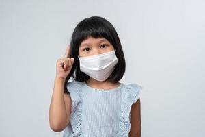 portret van een aziatisch meisje met een beschermend gezichtsmasker klaar voor het nieuwe schooljaar met pandemische beperkingen. concept van kind dat teruggaat naar school en een nieuwe normale levensstijl foto