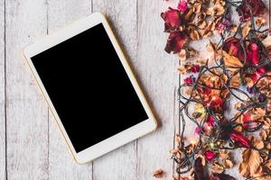 bovenaanzicht van tablet met gedroogde bloemen en kerstverlichting op houten tafel achtergrond. foto