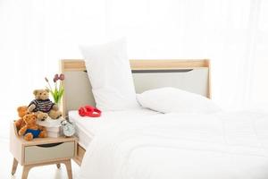 het moderne of minimalistische interieur van de slaapkamer, gedecoreerd met een comfortabel tweepersoonsbed, wit beddengoed zoals deken, kussens en houten meubilair foto