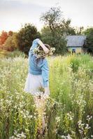 mooi meisje lopen op veld op zomer met wilde bloemen. foto