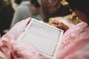 close-up van een moslimvrouw in een dagelijks gebed thuis die de heilige koran reciteert. moslimvrouw die de koran thuis bestudeert. foto