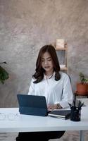 charmante Aziatische zakenvrouw zitten werken op laptop in kantoor. foto