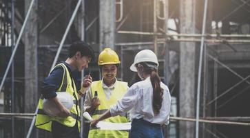 een divers team van experts plant op de bouwplaats. vastgoedproject met civiel ingenieurs, architecten, zakelijke investeerders en de generale staf bespreken de details van de plannen. foto