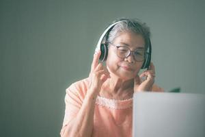 oude senior vrouw die graag een koptelefoon gebruikt foto