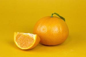 vers oranje fruit met geïsoleerd blad. oranje geheel, plak, blad op gele achtergrond. sinaasappelschijfje met geïsoleerd patroon foto