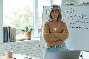 senior vrouw die in de buurt van het whiteboard in de klas staat foto