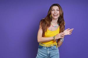 aantrekkelijke jonge vrouw die lacht terwijl ze tegen een paarse achtergrond staat foto