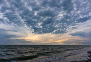 de avondlucht heeft wolken vol lucht, het licht van de zon reflecteert zeewater, zeeoppervlak foto