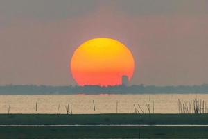 de grote zonsopgang is oranje. zonsopgang boven de zee en het mangrovebos foto