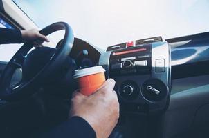 man rijdt auto terwijl hij een kop warme koffie vasthoudt - auto rijdt slaperig of in slaap concept foto