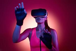 jonge vrouw in virtual reality-bril gebaren tegen kleurrijke achtergrond foto